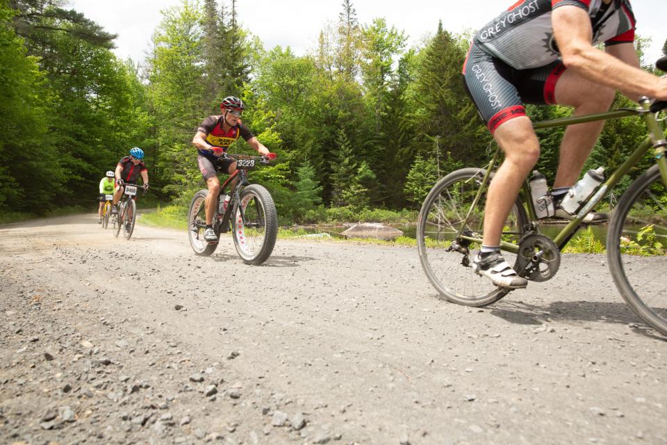 A group of cyclists ride on a gravel path.