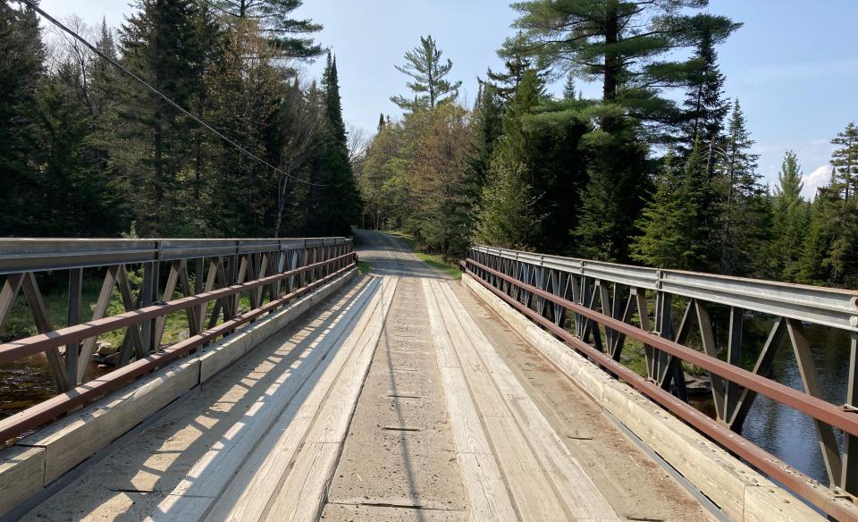 A wooden bridge leading to a wooded trail.