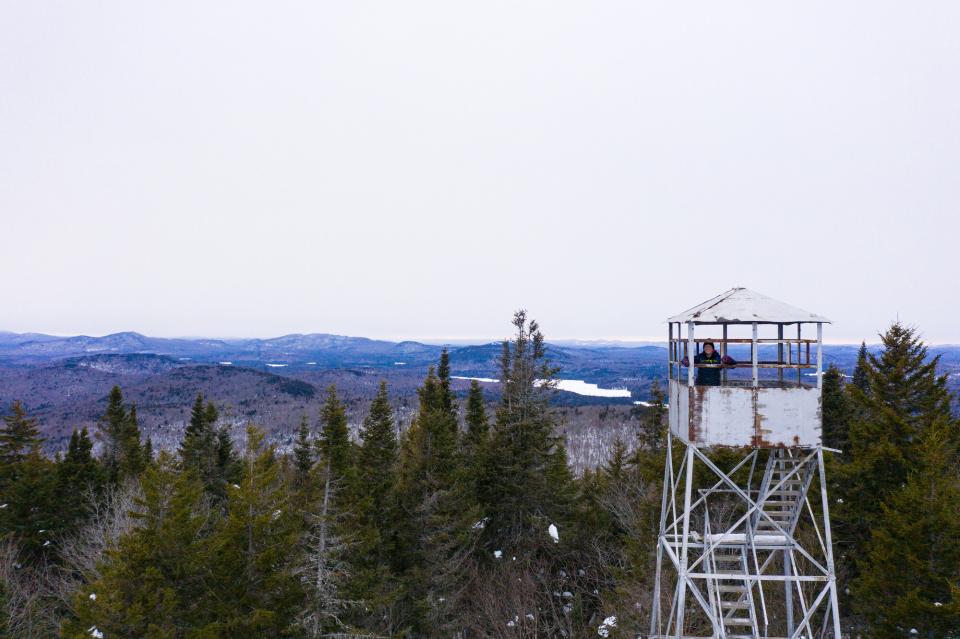 A person smiling atop a firetower in the winter
