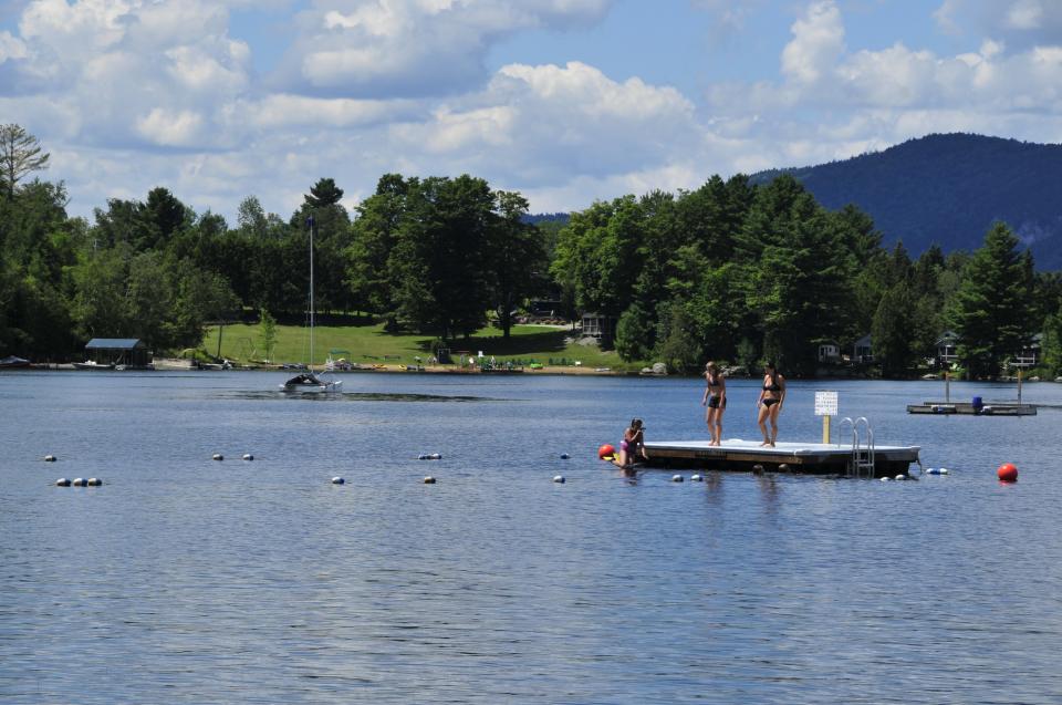Swimmers rest on a dock in the middle of a lake.