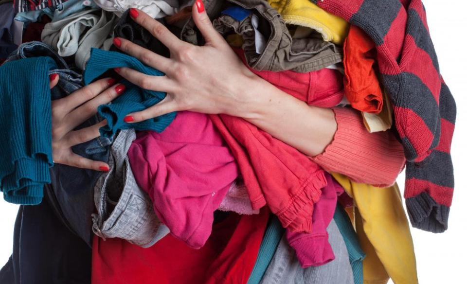 woman holding a large pile of clothes in her hands