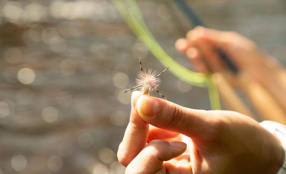 Woman holding a fly fishing fly in her fingers
