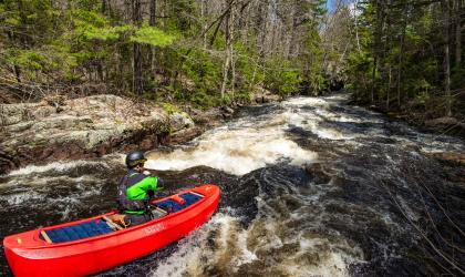 A whitewater kayaker heads towards some rapids.