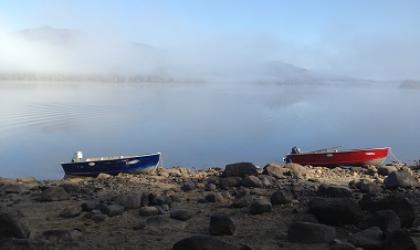Two boats resting on the shore of Indian Lake Islands State Campground on a foggy morning