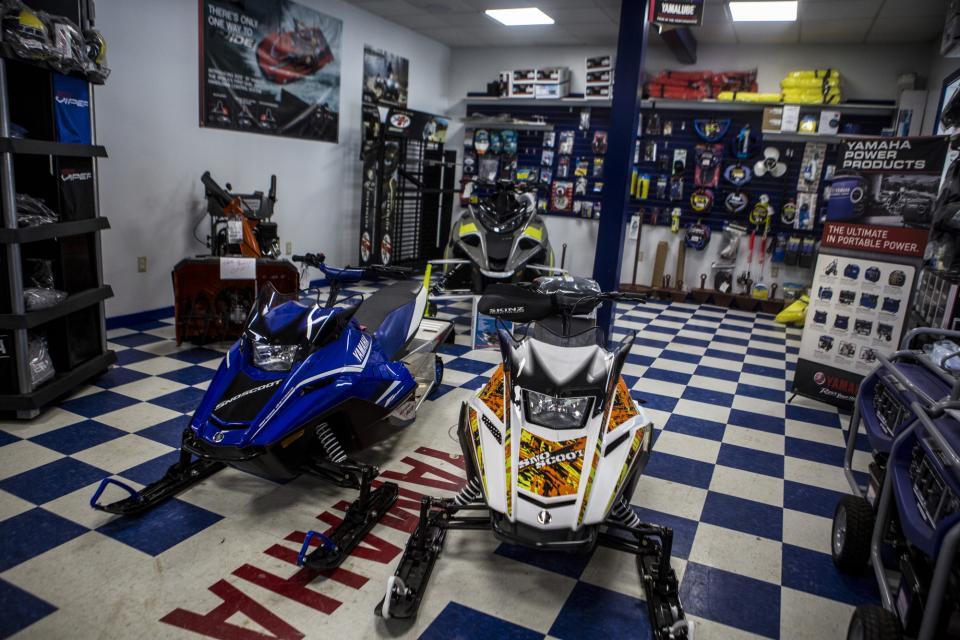The interior of a snowmobile shop, displaying snowmobiles, apparel, and accessories.