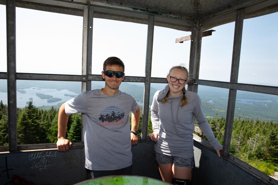 a man and woman pose for a picture in a  firetower.