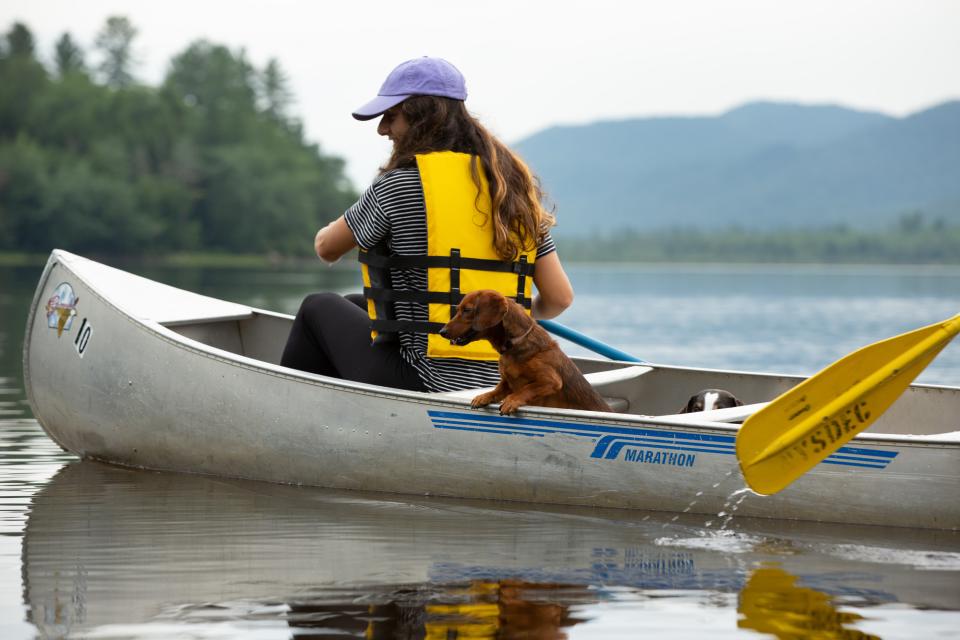 a woman and a dachshund dog paddle in a canoe.