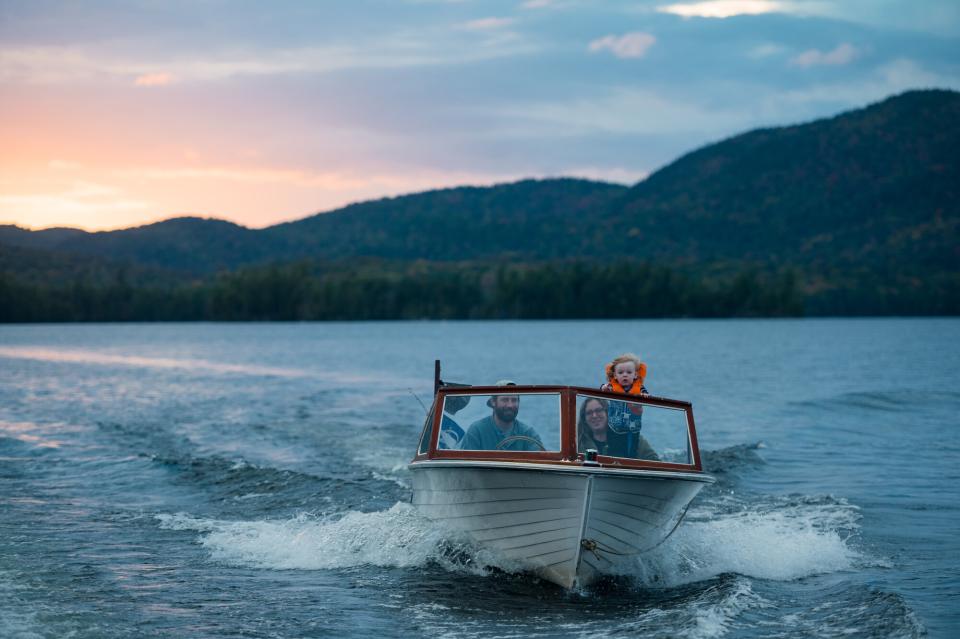 A family riding a motorboat on a lake at sunset with mountains in the background.
