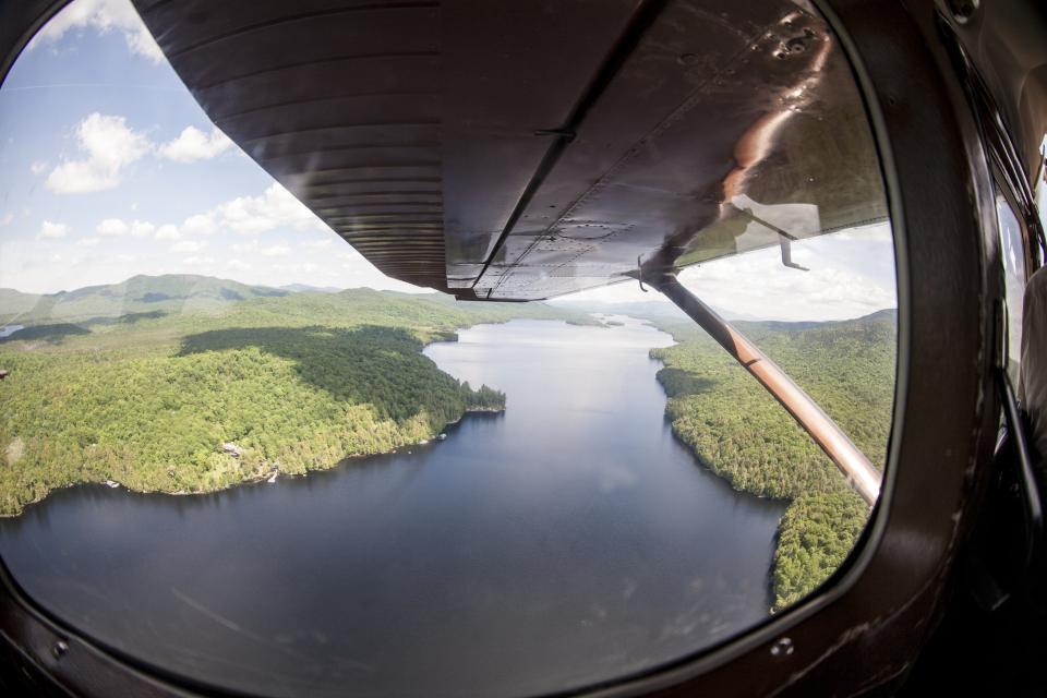 The view of a long lake and forests from a float plane in the Adirondacks.
