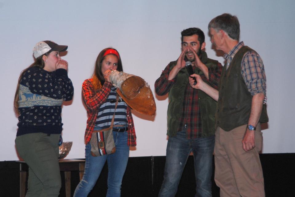 Four people participate in a moose call competition.