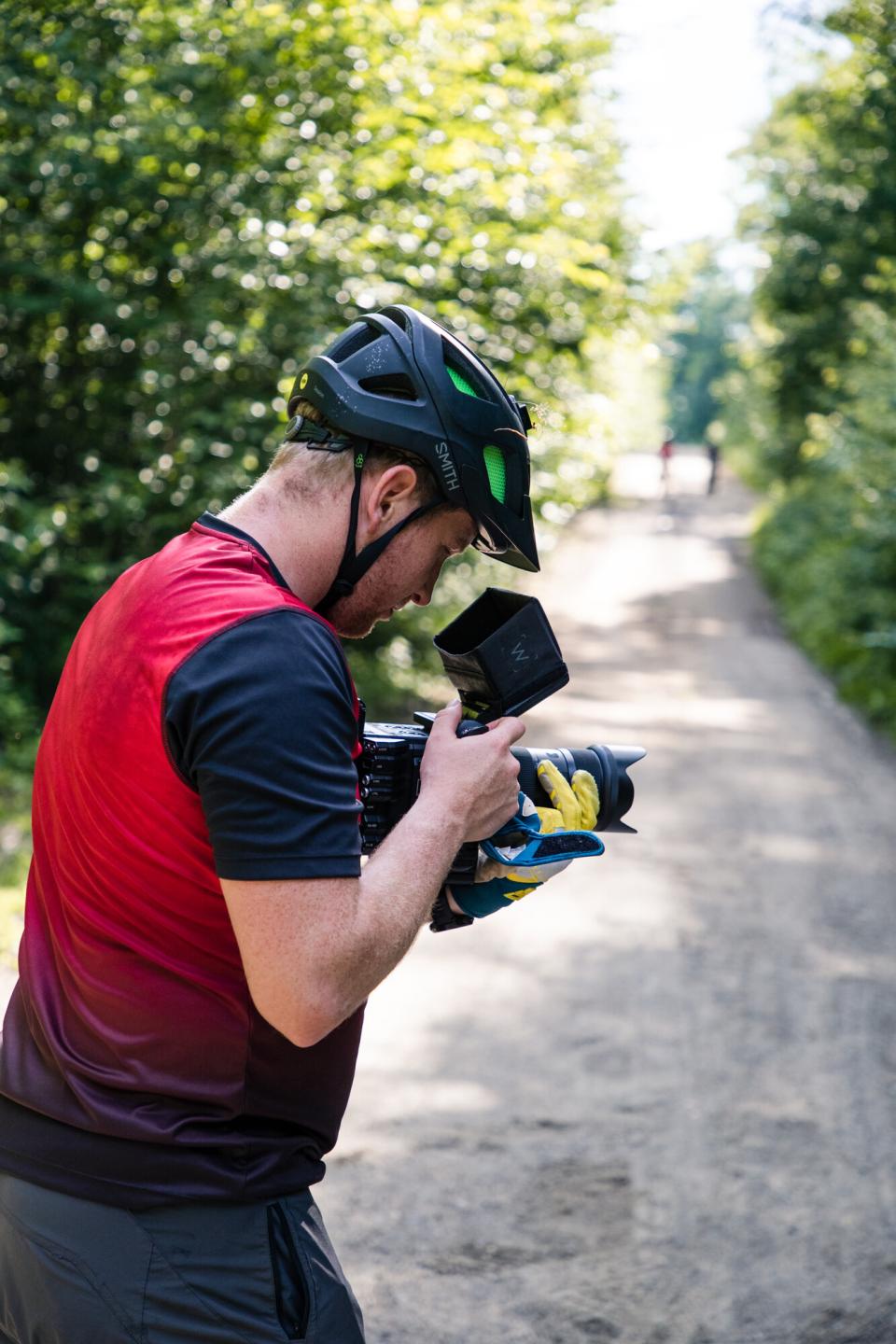 a man checks a camera in biking gear.