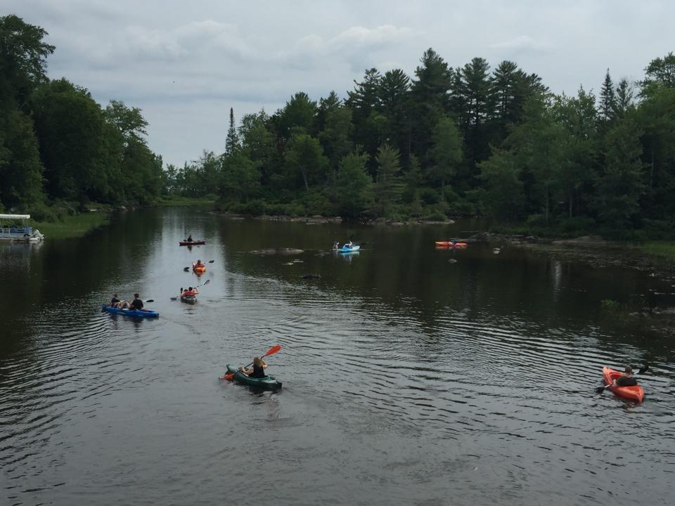 people kayak through a wide creek.