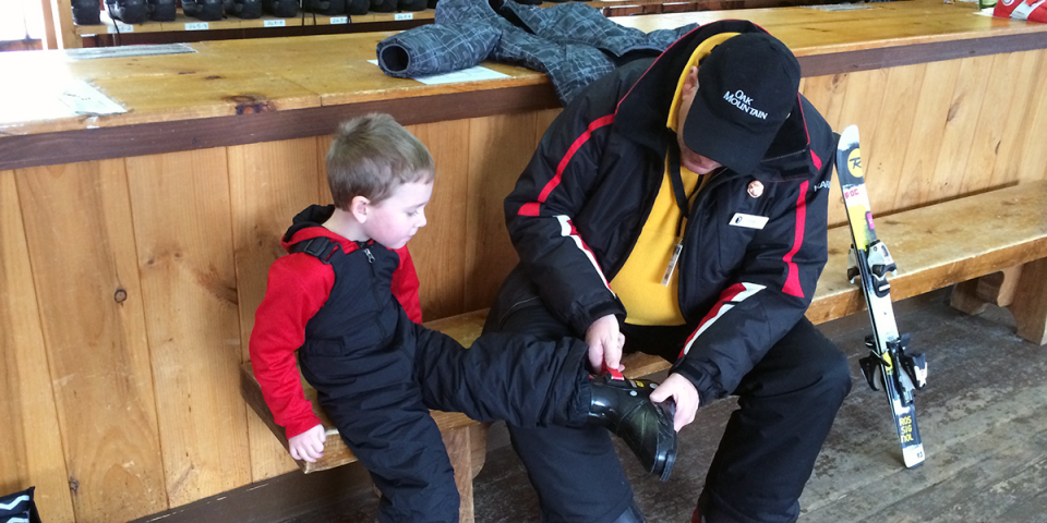 Elliot learns how to strap on boots in the Oak Mountain Rental Shop