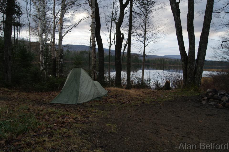 A tent set up by a waterside campsite