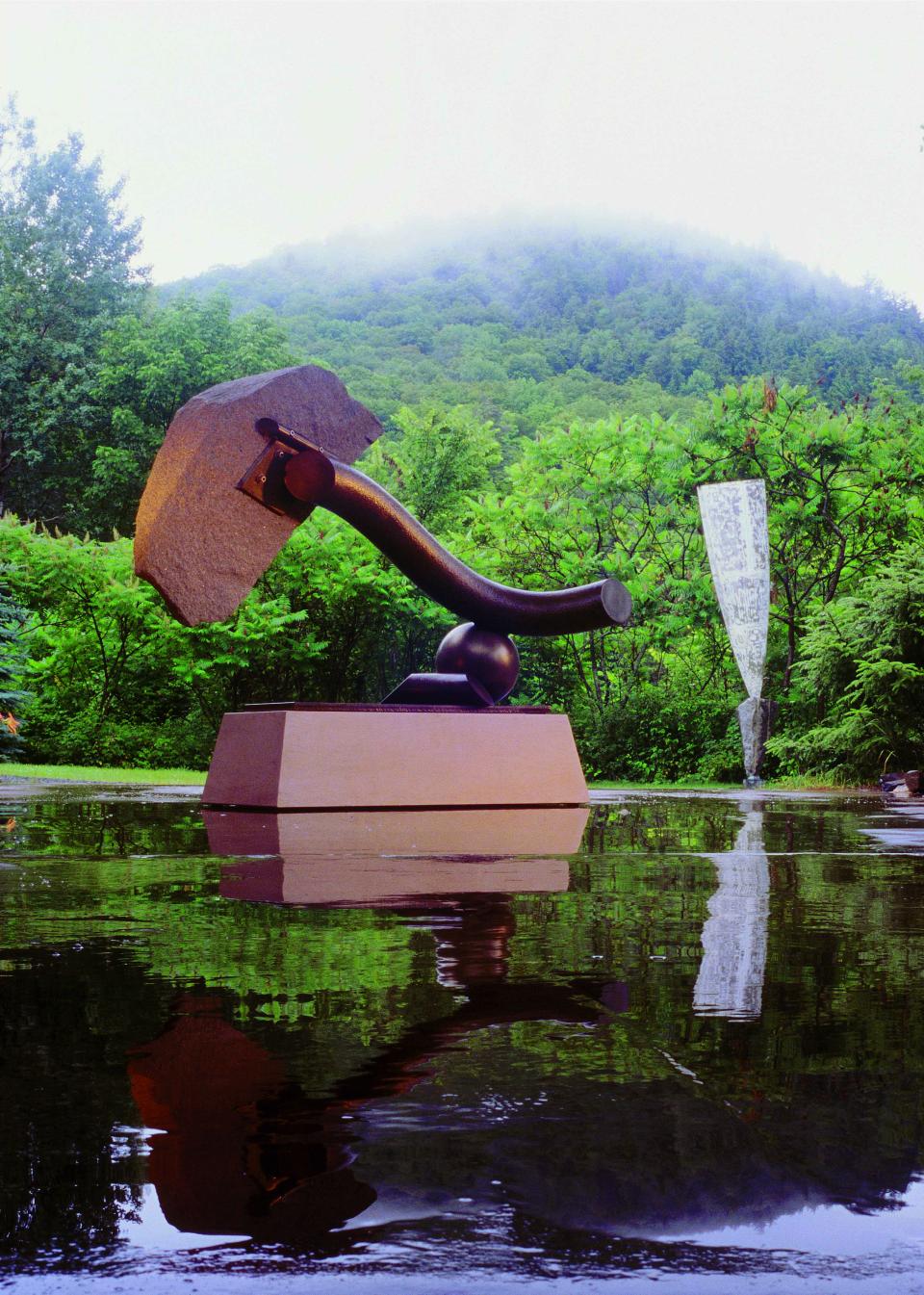 Here, a recent rain adds to the presence of the sculpture and the forest surroundings.
