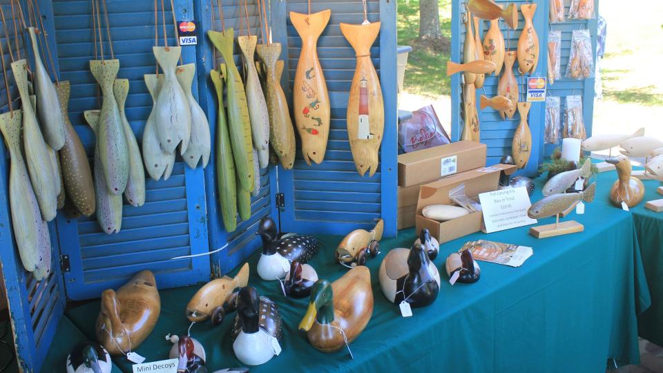 A display of carved wooden fish and duck decoys.