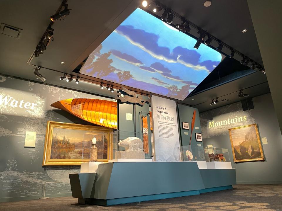 A dynamic museum exhibit space, with a painting on the ceiling and other items on display stands.