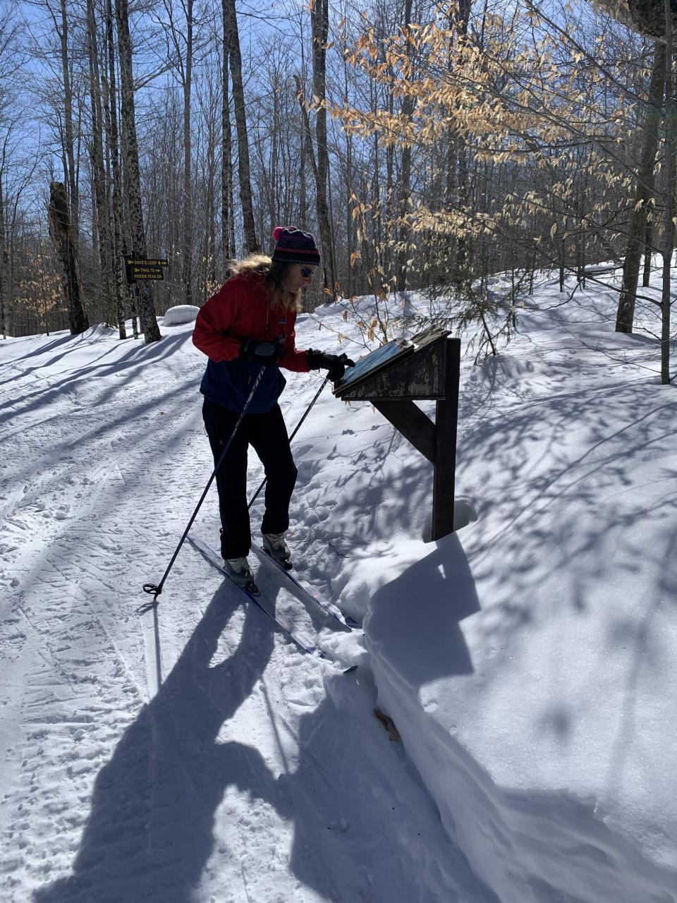 A woman signs in at the trail register on cross-country skis.