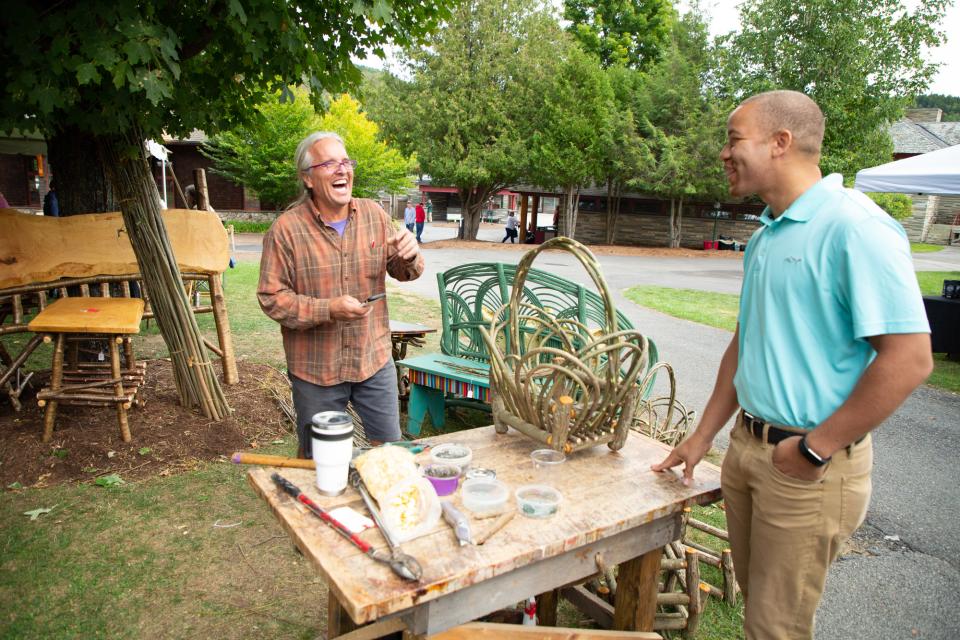 Two men laugh over a display at the annual ADKX Rustic Furniture Fair.