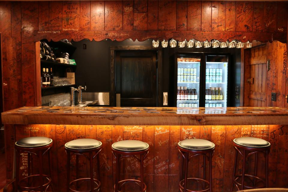A rustic wood bar covered by graffitied walls at Strong Rope Taproom.