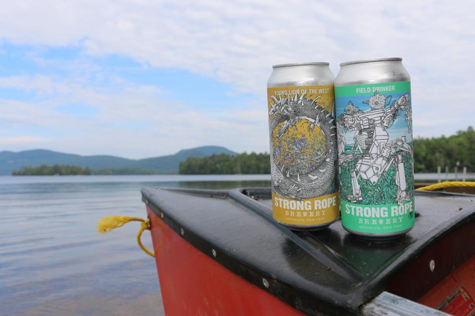 Two cans of Strong Rope beers sit on a boat on Blue Mountain Lake.