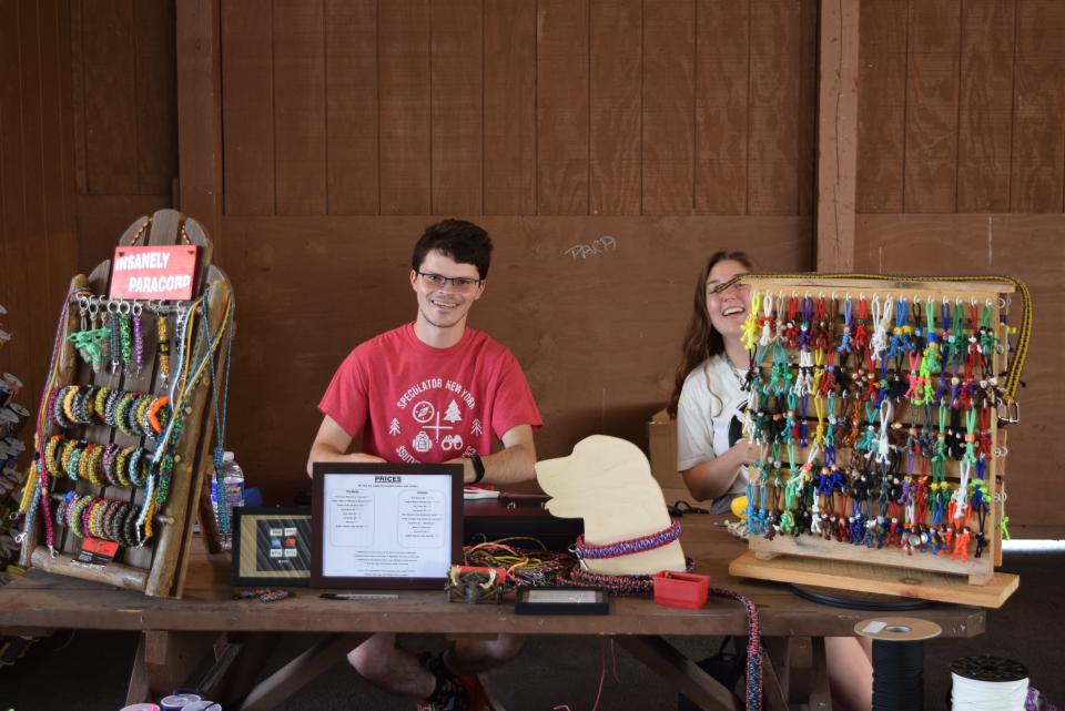 Vendors sit at a table filled with homemade safety rope items for sale