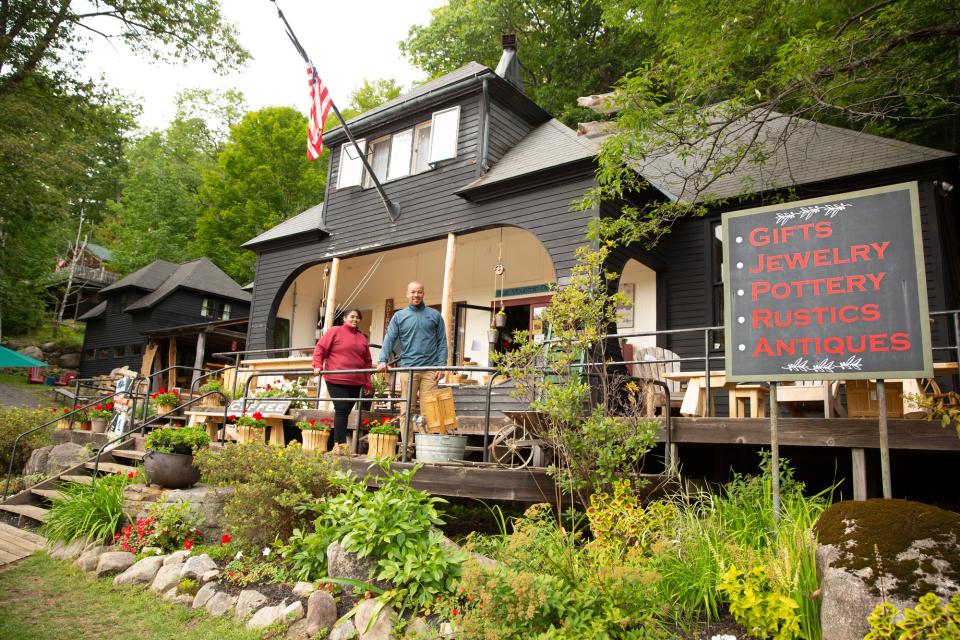 A couple outside a rustic shop surrounded by Adirondack greenery.
