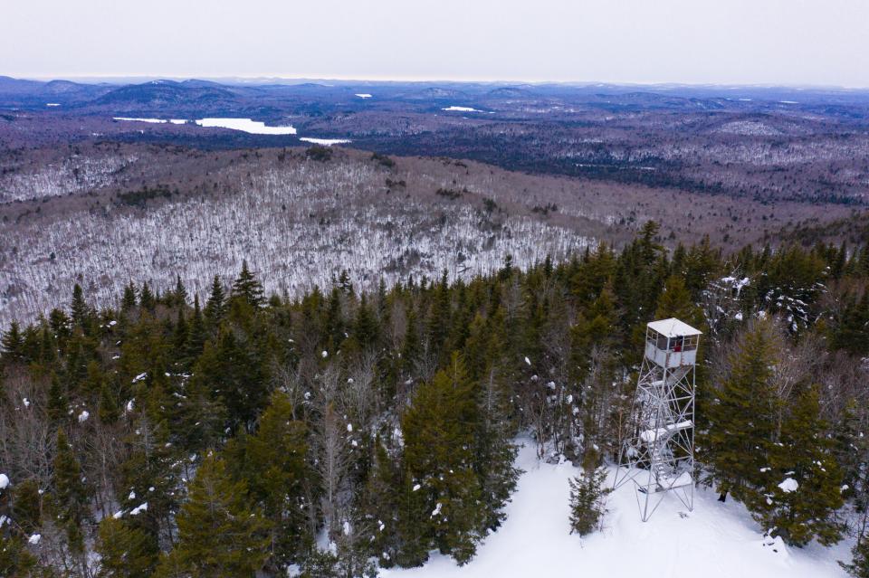 An aerial view of a fire tower with a sprawling winter landscape below.
