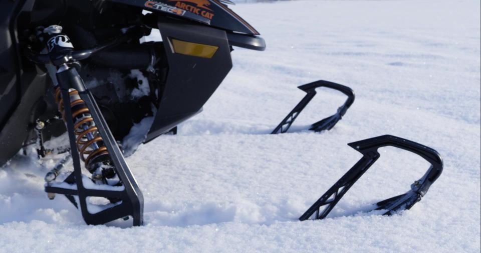 A closeup image of the front of a snowmobile resting in the snow