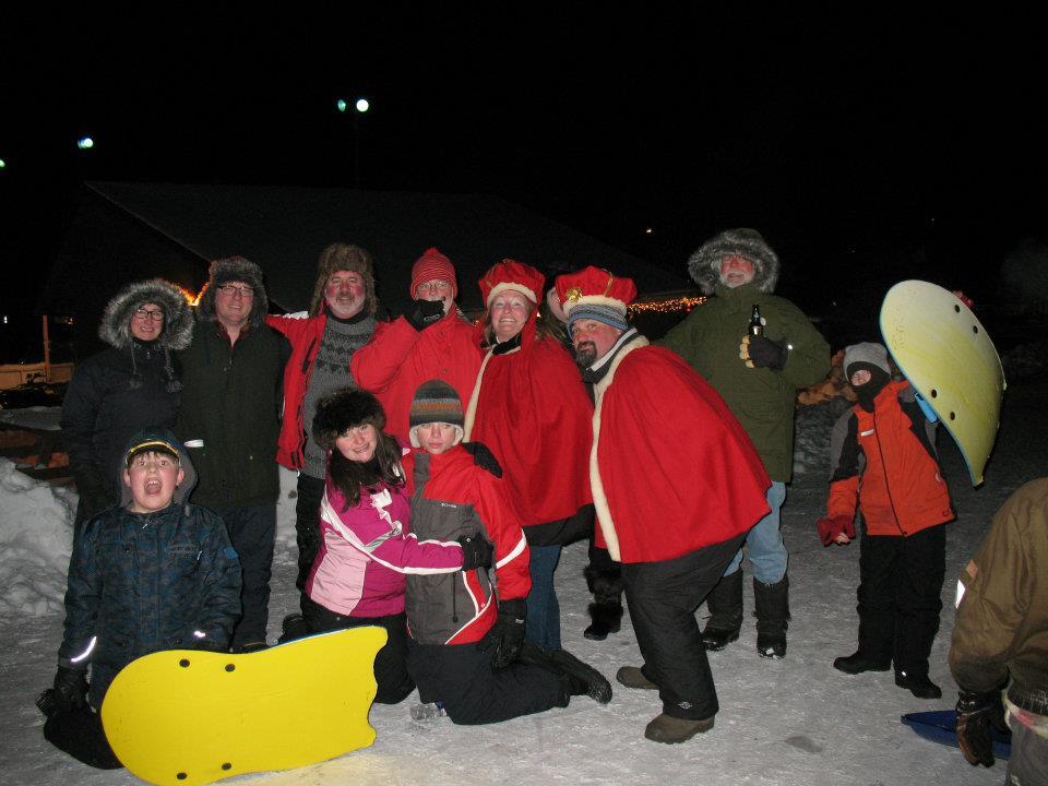 A group of people dressed in winter clothes and some in royal robes smile during winter carnival.