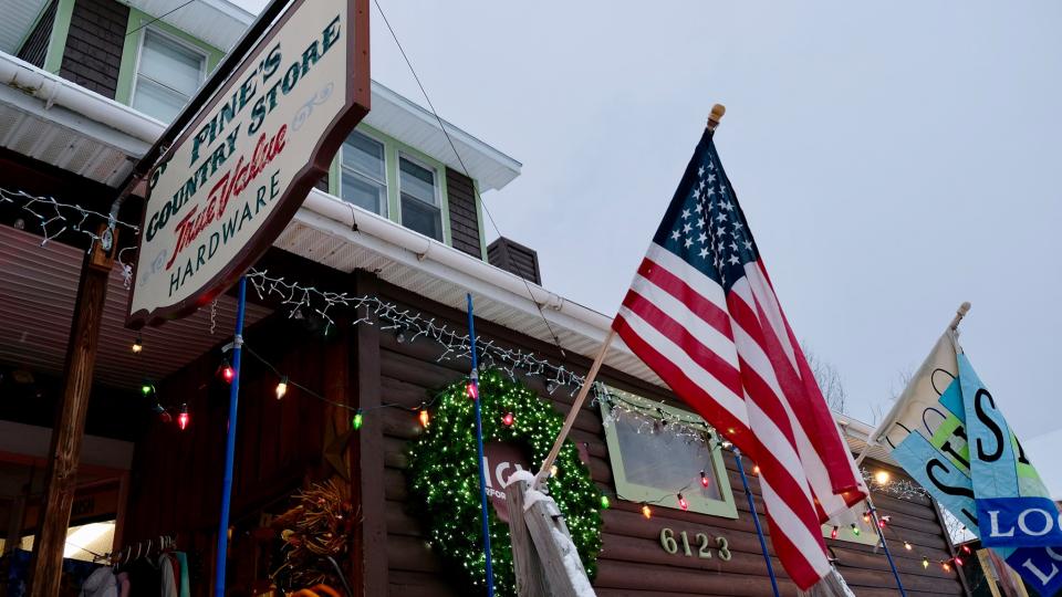 A store front with colorful Christmas lights and an American flag.