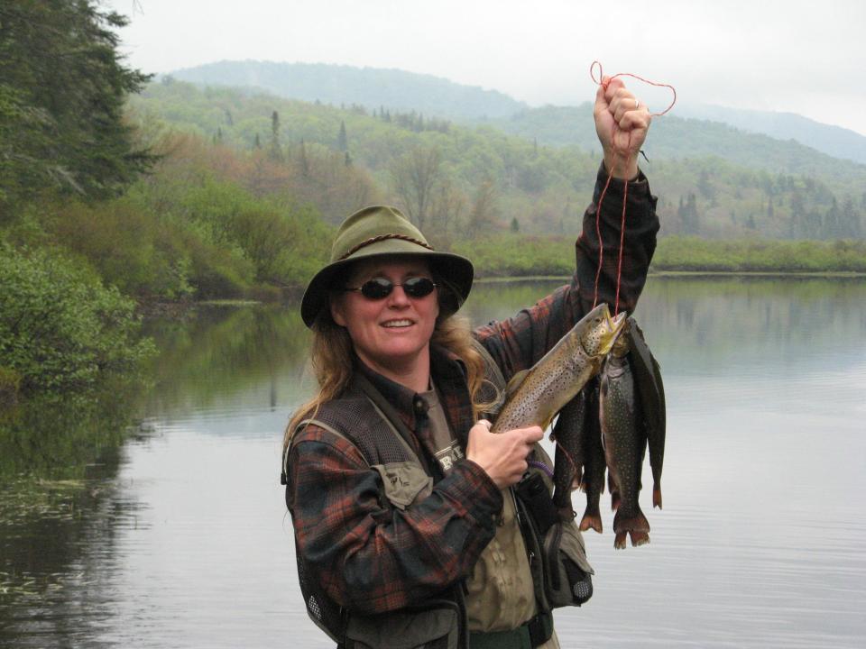 A woman showing off her catch of brook trout.