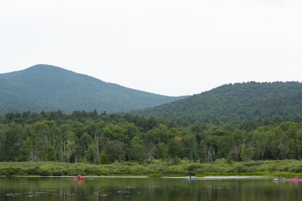 A wide view of canoeists paddling on an Adirondack lake.