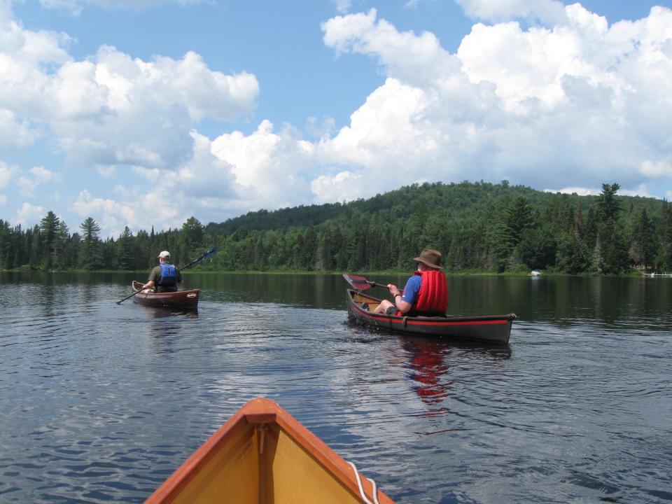 Canoeists on a tranquil lake with mountains beyond.