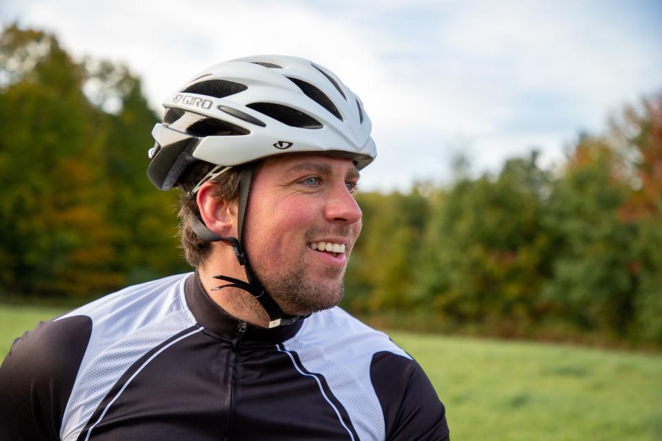 A man wearing a bike helmet smiles.