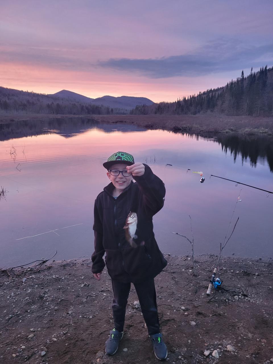 A child holds up a freshly caught fish at sunset