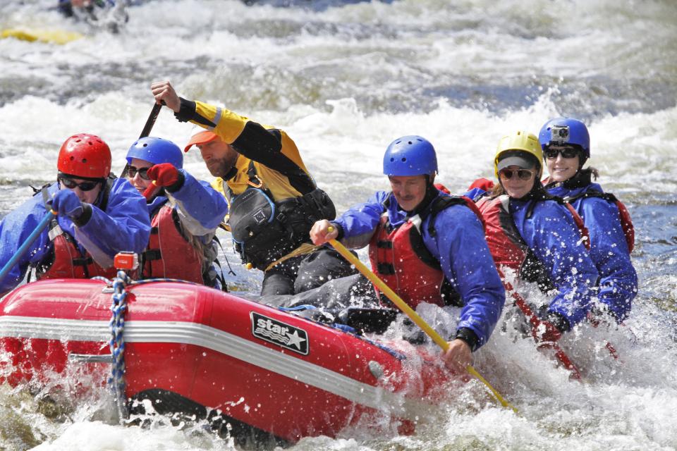 A team of people paddle through rapids.