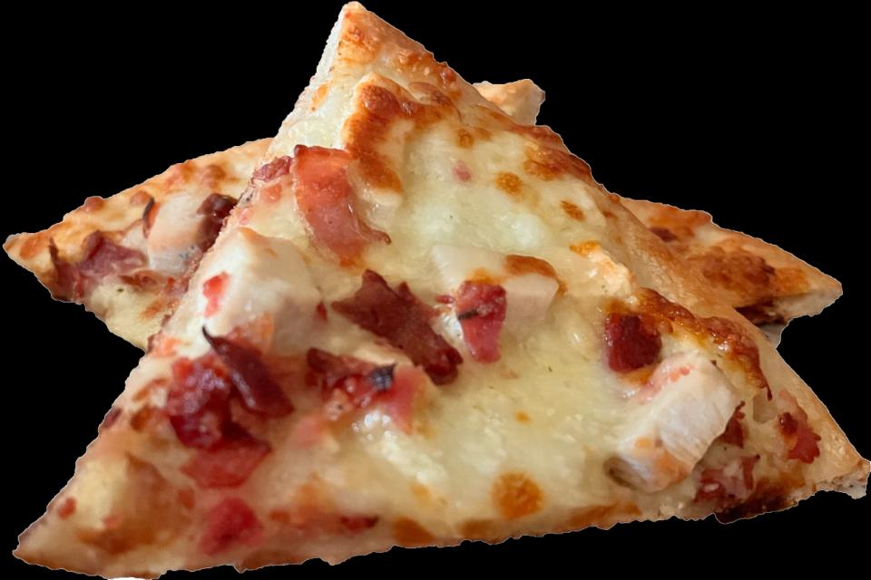 Slices of pizza with bacon and chicken against a black background.