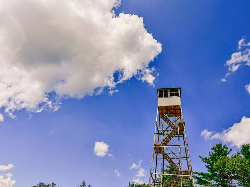 A fire tower against a blue sky with a few clouds.