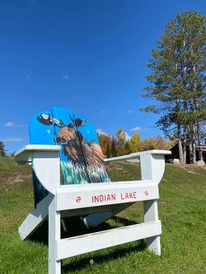 An Adirondack Chair with a moose painting and Indian Lake words
