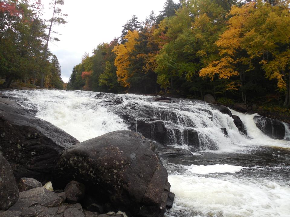 Waterfalls on a river surrounded by fall foliage.