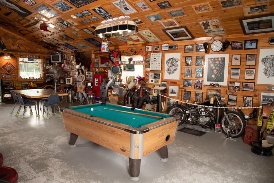 The interior of a rustic saloon with walls and ceiling decorated in signs, motorcycle parts, and more.