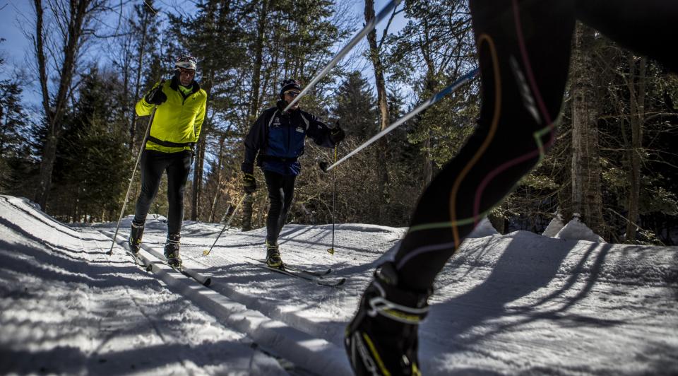 Three cross-country skiers race on a snow path.