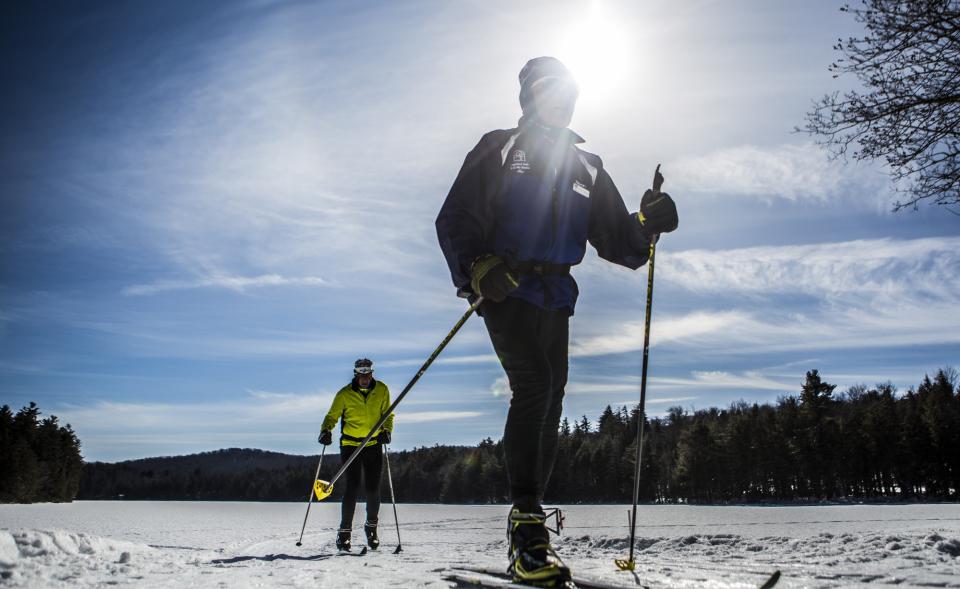 Two skiers ski on a frozen lake.