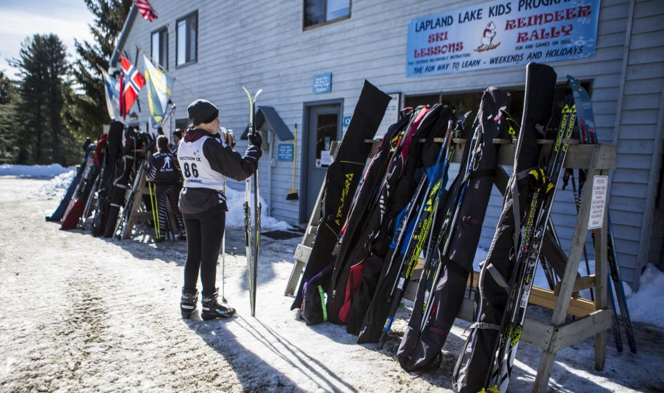 A skier selects skis from an outdoor rack.