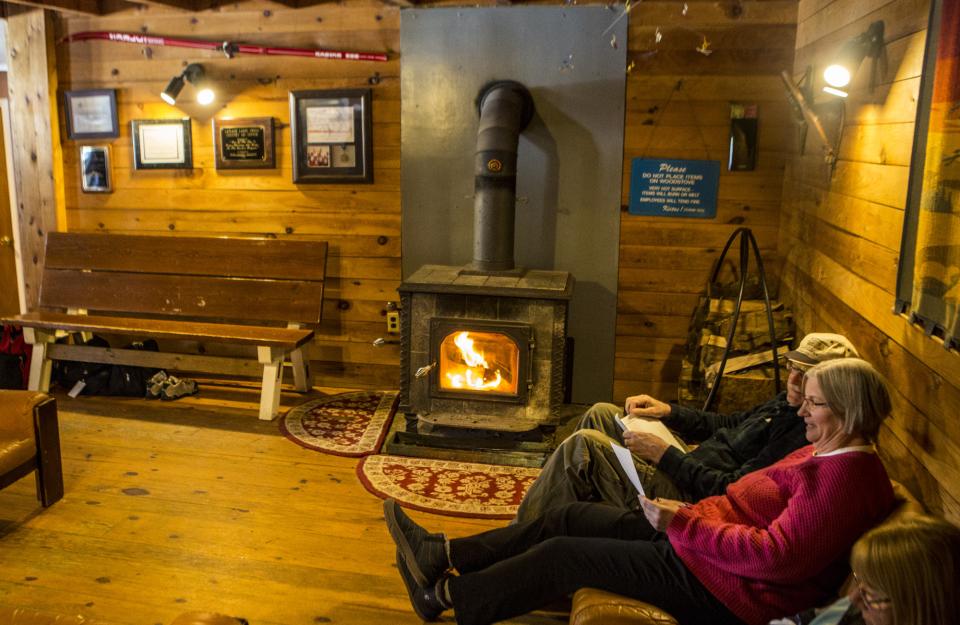 A couple sits by a fireplace in a cozy lodge.