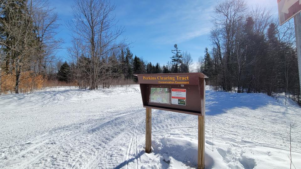 Sign for Perkins Clearing Tract in a snowy clearing in woods.