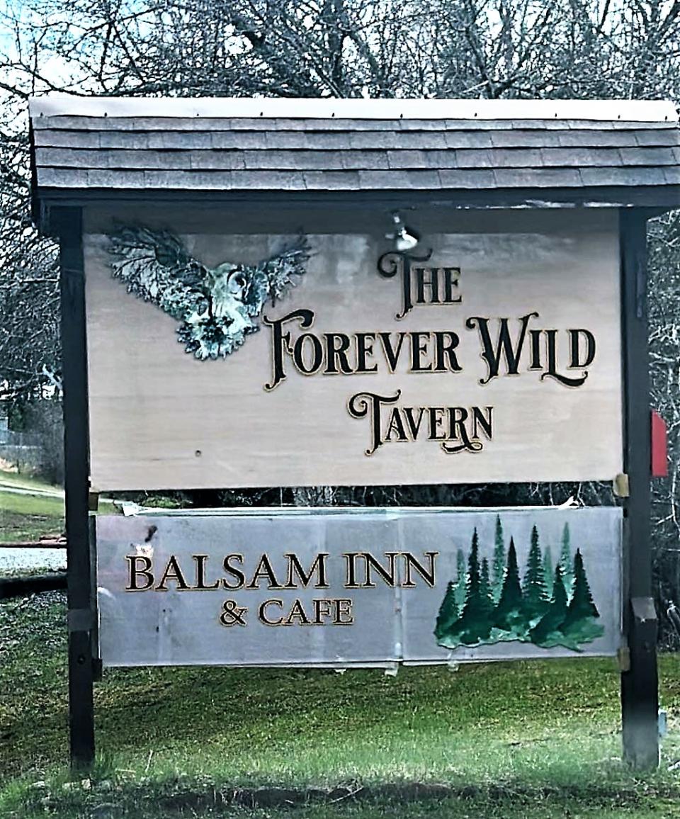 The Forever Wild Tavern sign with trees in the background.