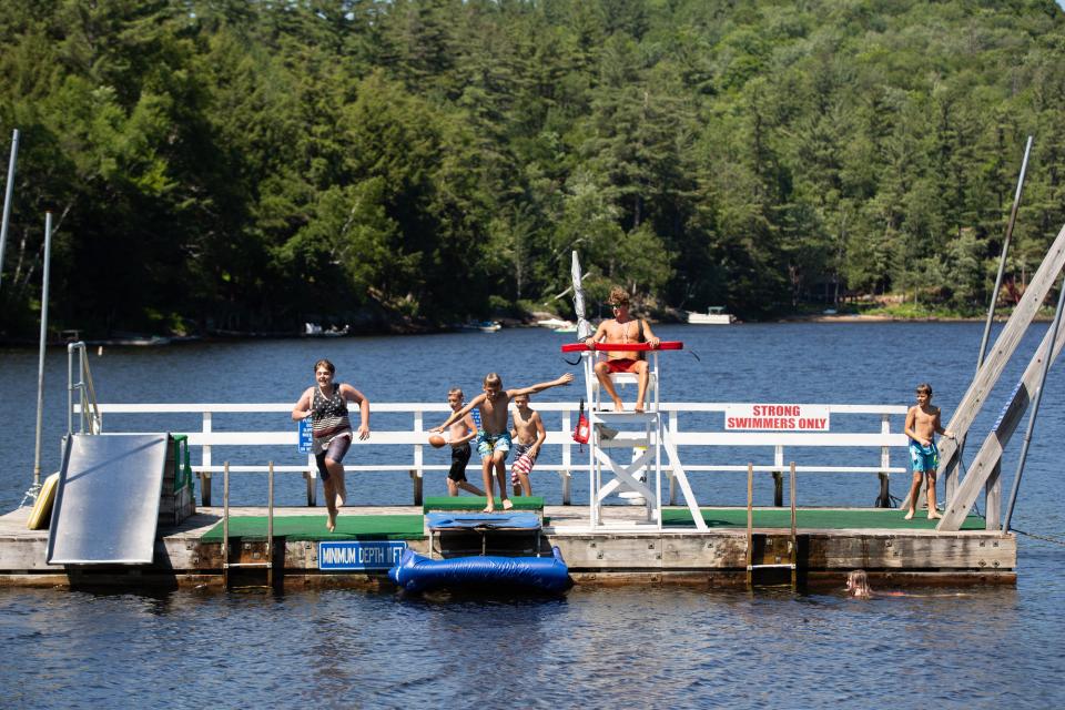 Swimmers jump into the water from a dock