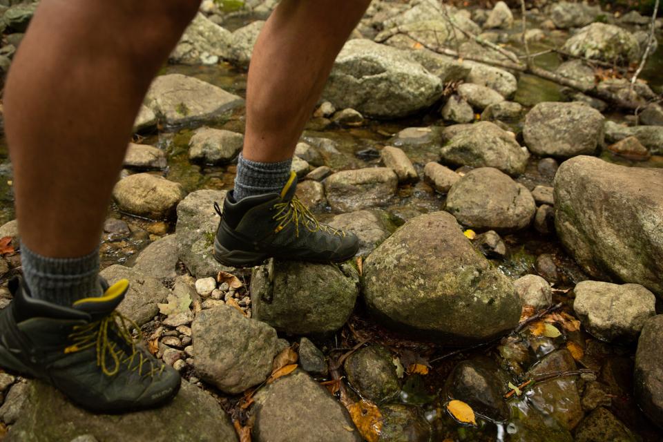 A hikers boots going across a rocky, dry streamt